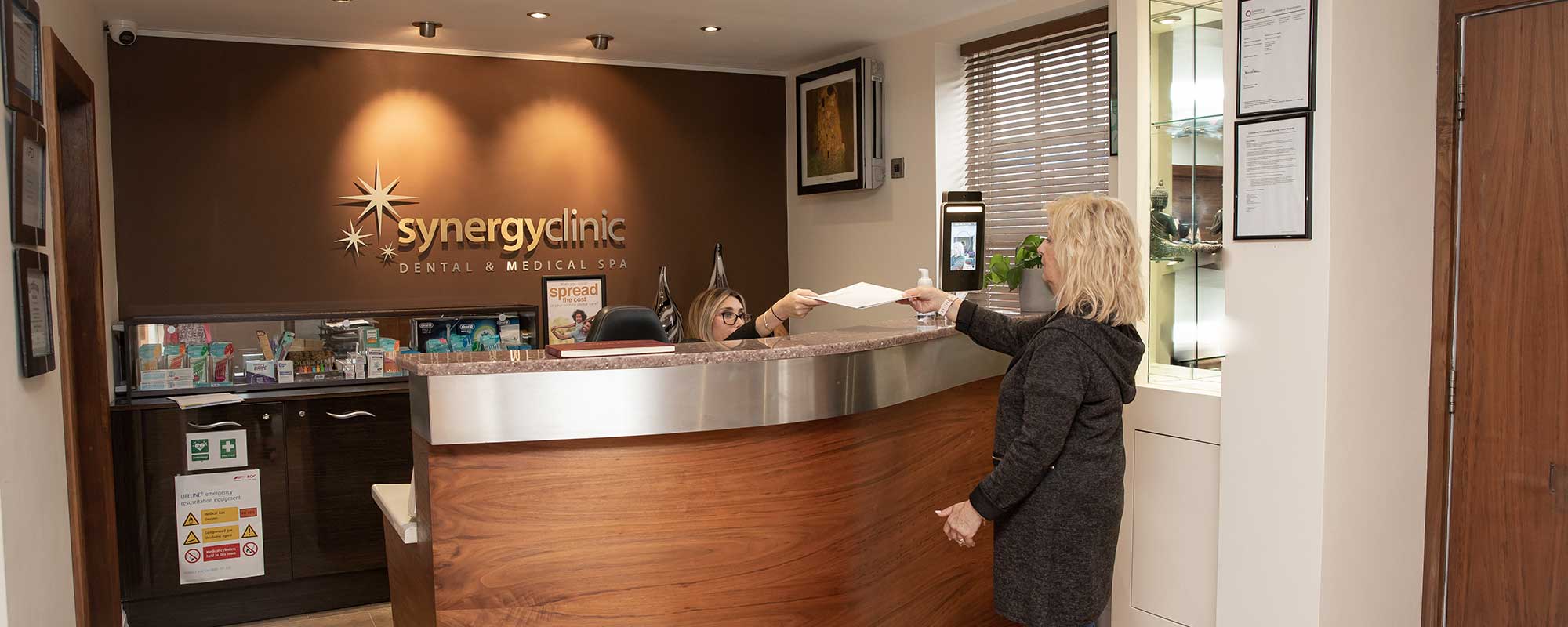 women handing a piece of paper over to the receptionist at Sync Clinic